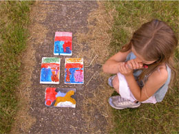 child looking at plaques she had painted